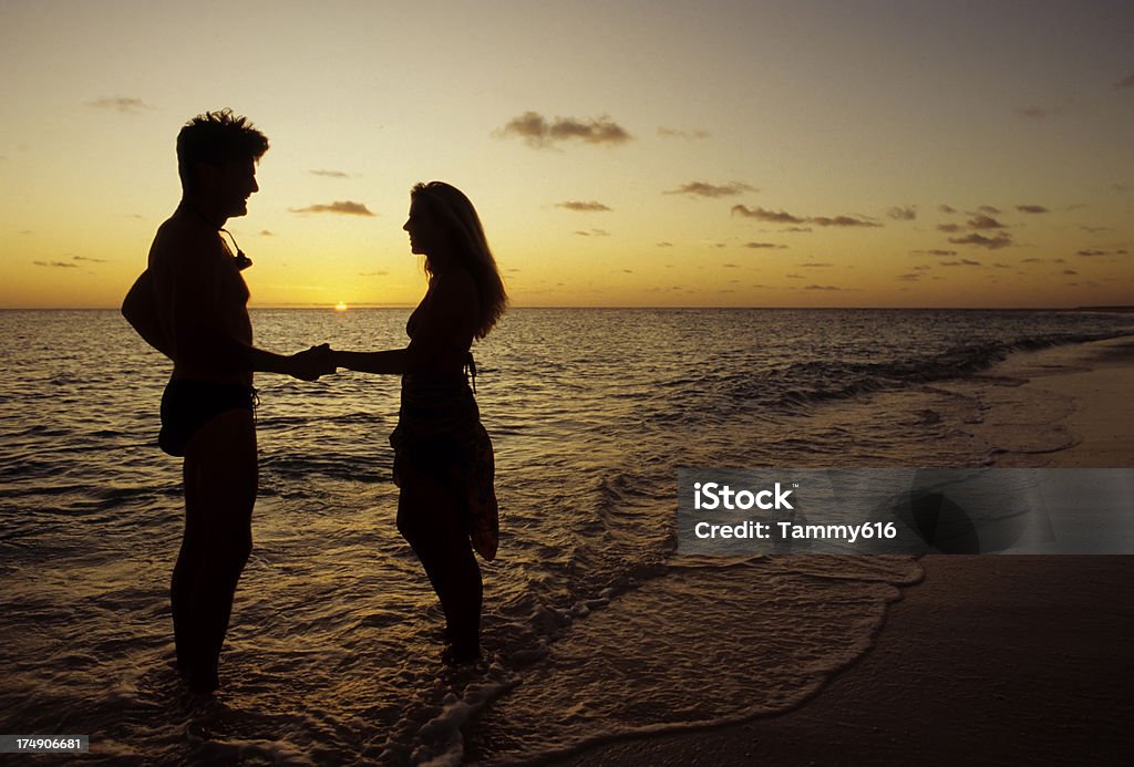 Romantic Couple Romantic scene of couple holding hands on beach. Adult Stock Photo