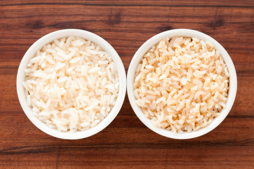 Top view of two bowls containing white and brown boiled rice