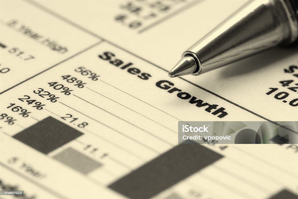 A graph displaying sales growth for a business with a pen Closeup of ballpoint pen on sales growth graph (very shallow dof; focus on pen tip). Aspirations Stock Photo