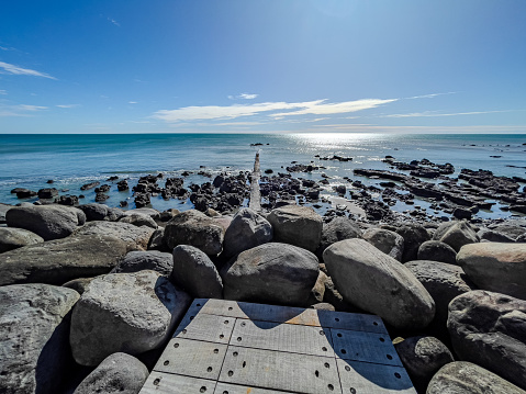 Wooden boardwalk facing out to sea on a sunny day.