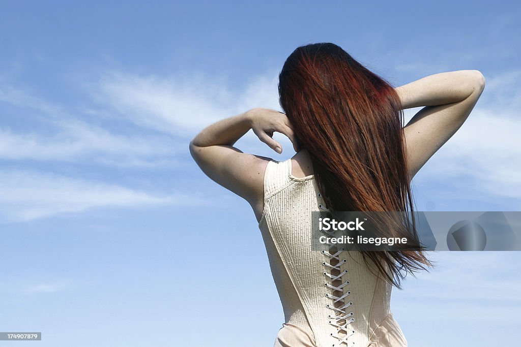 Mulher vestindo um espartilho brincando com seu cabelo. - Foto de stock de Adolescente royalty-free