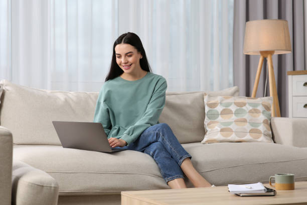 istock Happy woman working with laptop on sofa at home 1749079143