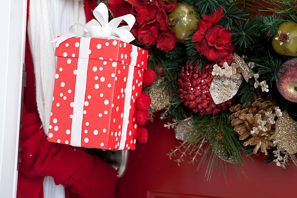 A person standing at the doorway with a gift in their hand