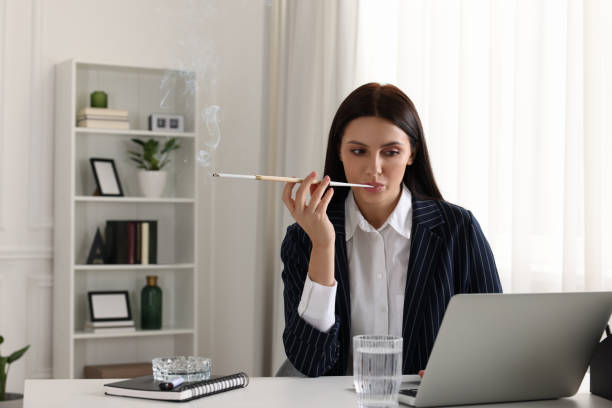 istock Woman using long cigarette holder for smoking at workplace in office 1749088807