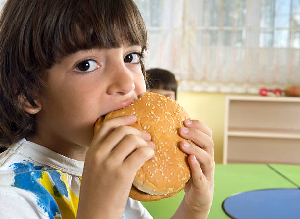 istock little caucasian boy eating burger 174909519