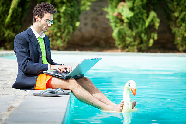 Businessman using laptop and relaxing in swimming pool