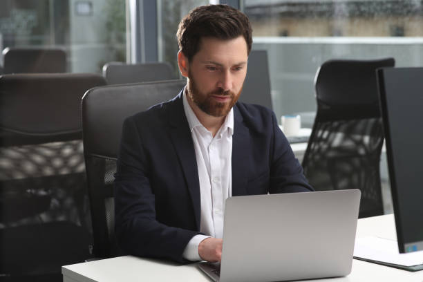 istock Man working on laptop at white desk in office 1749104005