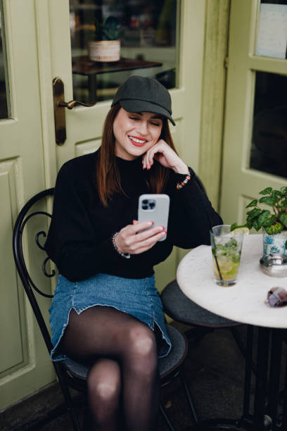 istock Smiling woman using a smartphone in a sidewalk bar on an autumn day 1749107465