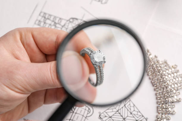 istock Jeweler examining diamond ring with magnifying glass at white table, closeup 1749117031