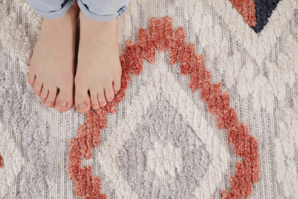 istock Woman standing on carpet with pattern at home, top view 1749117575