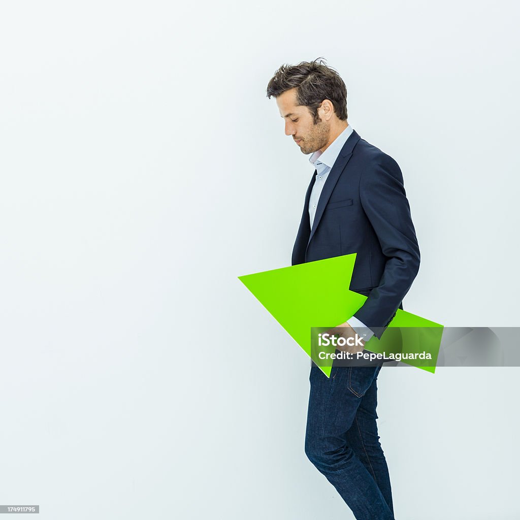 Businessman holding a green arrow Middle aged businessman carrying a green arrow. Arrow Symbol Stock Photo