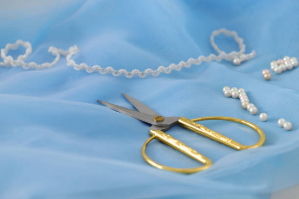 istock Pair of scissors and white beads on light blue fabric, closeup 1749118107