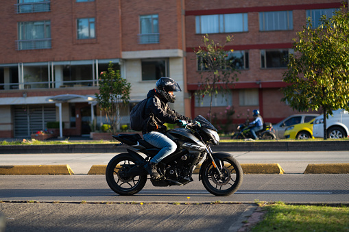 Motorcyclist with a helmet on an avenue in the Colombian capital in the evening light. Bogota. Colombia . July 18, 2023.