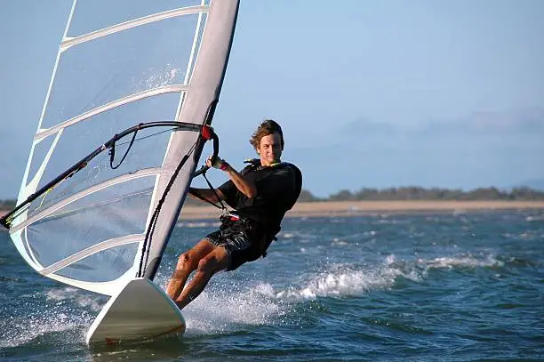 Young man windsurfing with trailing wake. Click to see more...