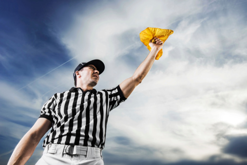 A football referee holding a yellow flag against the sky.  He is calling the penalty.   http://dl.dropbox.com/u/40117171/sport.jpg