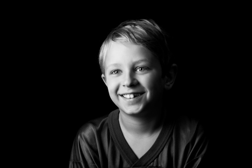 Portrait of a happy beautiful boy isolated on black background. Horizontal composition.