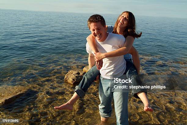 Middle Aged Couple Playing On The Beach Stock Photo - Download Image Now - Adults Only, Beginnings, Bonding