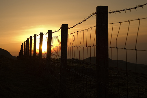 An old, rural fence against a sunset background.