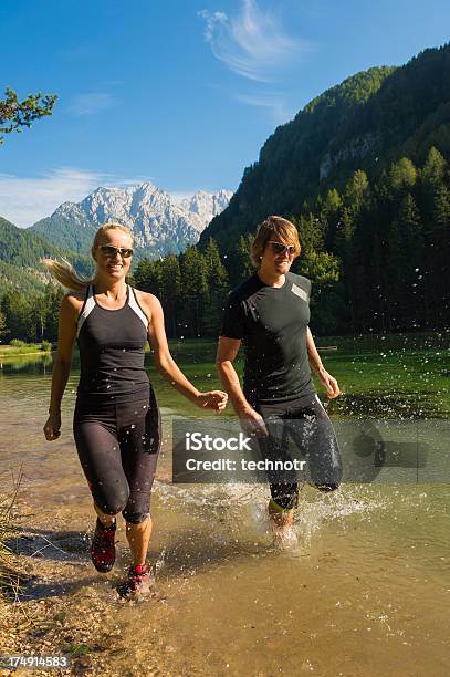 Giovane Coppia Che Corre Dal Lago - Fotografie stock e altre immagini di 20-24 anni - 20-24 anni, Adulto, Alpi