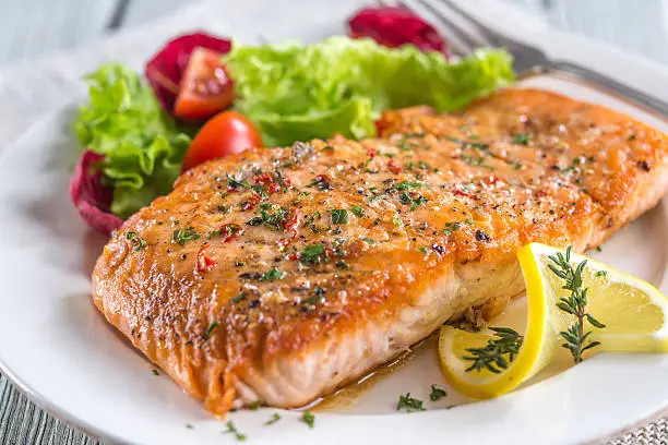 Photo of Beautiful plated salmon fillet with salad and lemon garnish