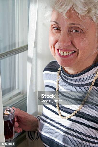 Mulher Idosa Sorrisos A Janela - Fotografias de stock e mais imagens de 60-64 anos - 60-64 anos, 65-69 anos, 70 anos