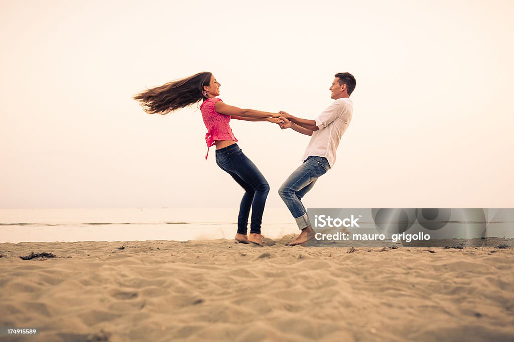 Coppia sulla spiaggia al tramonto - Foto stock royalty-free di 20-24 anni