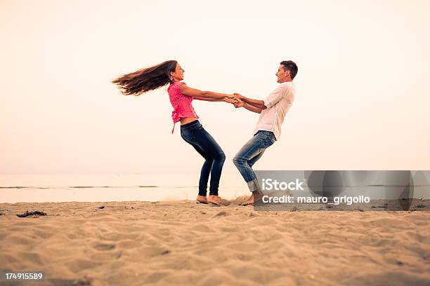 Coppia Sulla Spiaggia Al Tramonto - Fotografie stock e altre immagini di 20-24 anni - 20-24 anni, Abbigliamento casual, Acqua