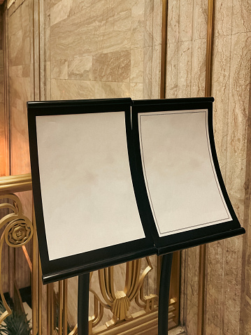Empty sign display with black metal frames holding parchment paper. Elegant golden background. Plenty of room for your own design and copy.