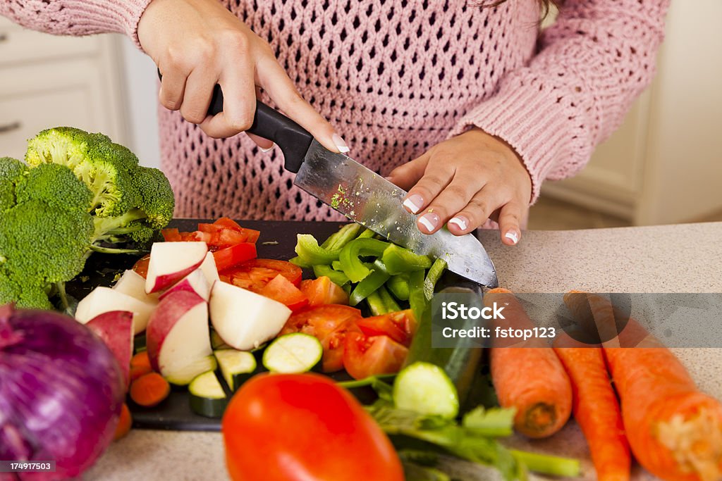 Giovane donna Latina Tagliare a pezzetti verdure per pasto salutare - Foto stock royalty-free di Adulto