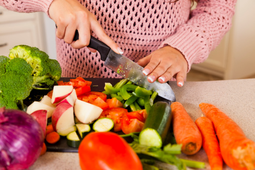 Young Latin woman chopping vegetables for healthy meal.