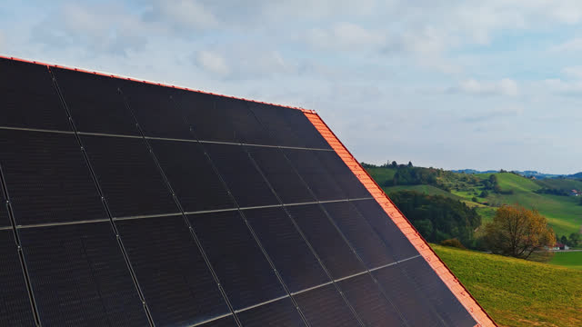 AERIAL drone shot of photovoltaic solar panels on House Roof near vineyard under cloudy sky