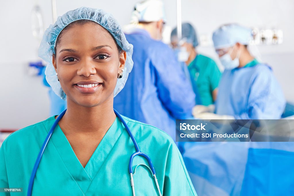 Confident surgical nurse; surgery being performed in hospital Hair Net Stock Photo