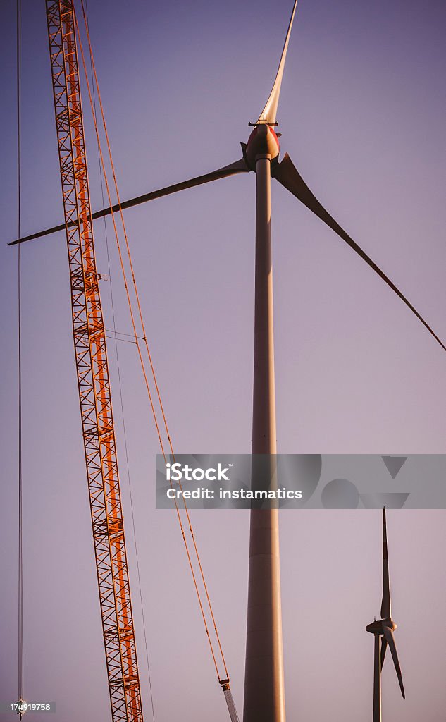 Два ветра турбины с Строительный кран на закате - Стоковые фото Ветряная электростанция роялти-фри