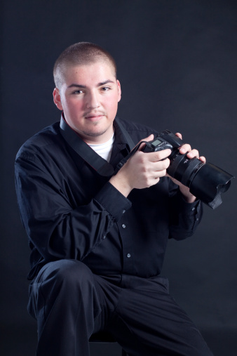 Smiling young hispanic male photographer with a camera.