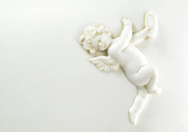 Porcelain cherub or putti with wings playing the tambourine on a white background with copy space.