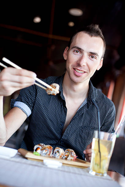 Happy Young Men Eating Sushi stock photo