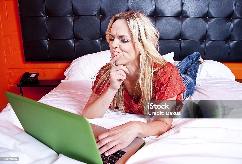 Donna con una Lap Top a letto - Foto stock royalty-free di Abbigliamento casual