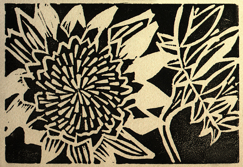 Linoleum cut print done in black ink on khaki paper of two sunflowers.