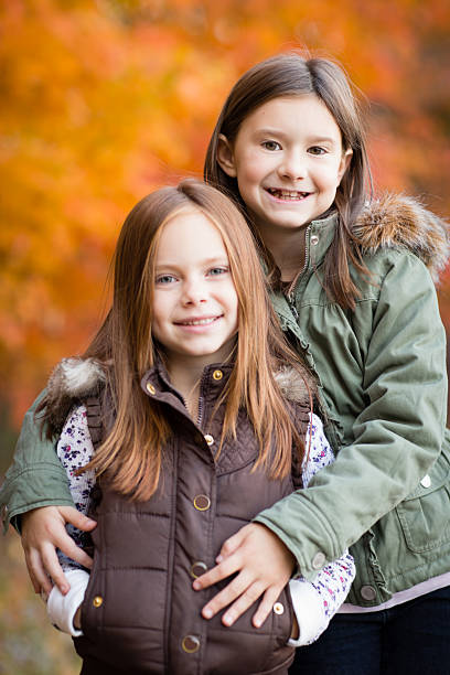 duas irmãs mais jovens em pé do lado de fora, em dia frio, outono - little girls autumn child red hair - fotografias e filmes do acervo