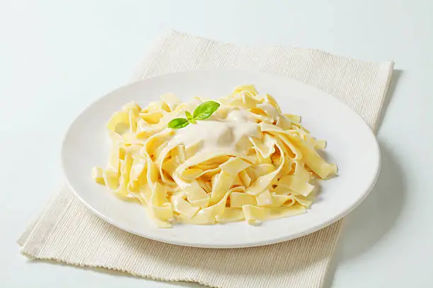 plate of freshly boiled pasta tagliatelle with a light dressing on a white placemat