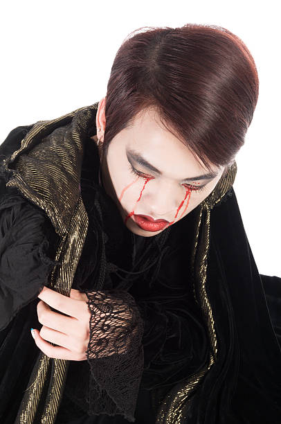 Vertical studio shot on white of Asian vampire crying bloody tears.