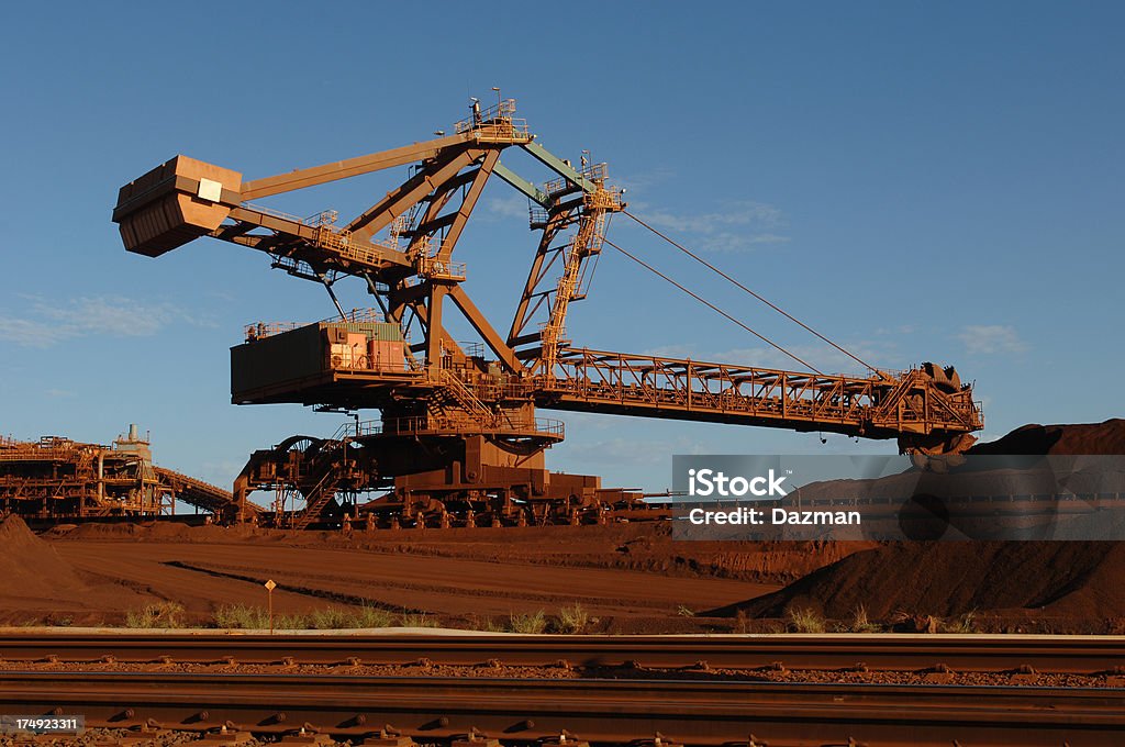 Iron ore reclaimer working in a stockyard. A rear view of a reclaimer used to harvest crushed iron ore stockpiles on a mine site. Iron Ore Stock Photo