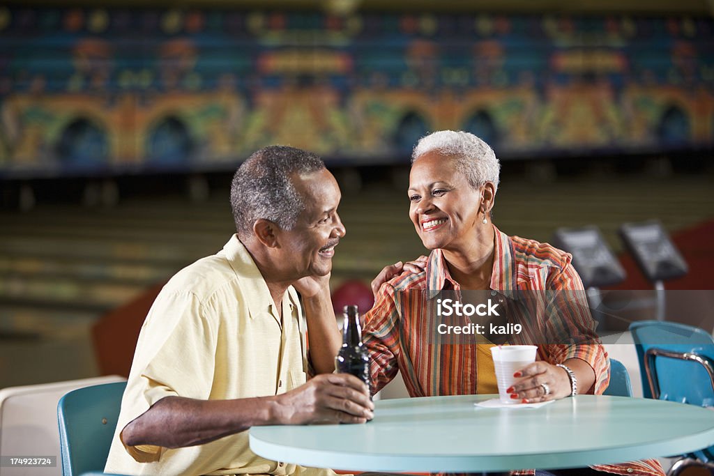 Senior couple in bowling alley African American senior couple (60s) having refreshments in bowling alley.  Main focus on woman. Beer - Alcohol Stock Photo