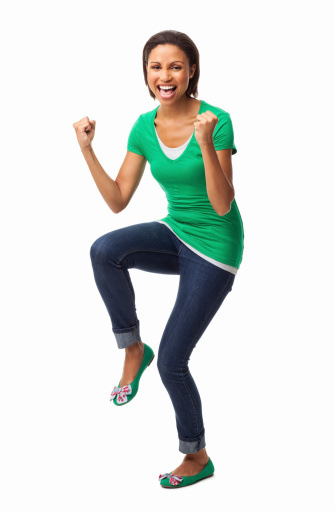 Full length portrait of an exhilarated African American woman in casual wear cheering up with clenched fists. Vertical shot. Isolated on white.