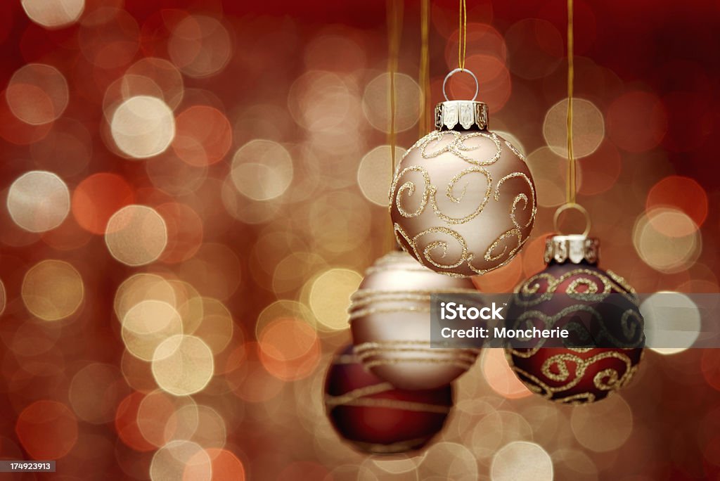 Accrocher des boules de Noël or sur fond rouge lumière - Photo de Artificiel libre de droits