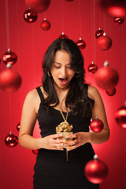 istock Surprised Hispanic Model in Black Dress Holding Christmas Present Vt 174924038