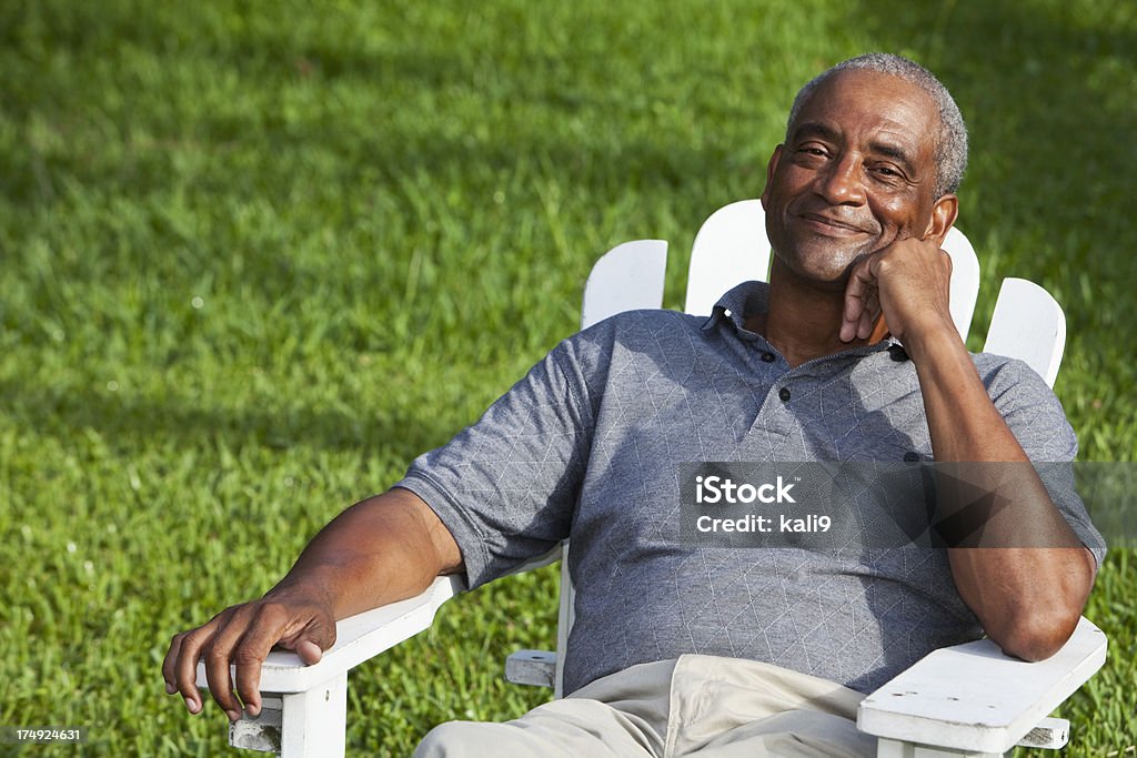 Senior Afro americano uomo seduto nella Sedia adirondack - Foto stock royalty-free di Ambientazione esterna