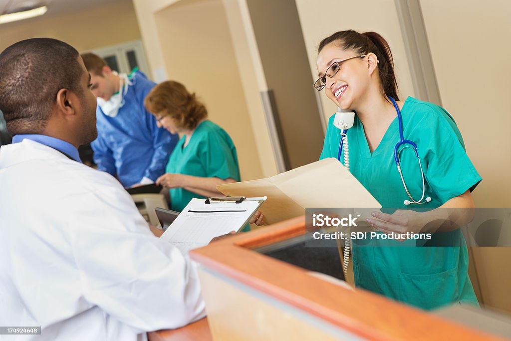 Infermiere/a al telefono e guardando i documenti per il medico - Foto stock royalty-free di Gabbiotto delle infermiere
