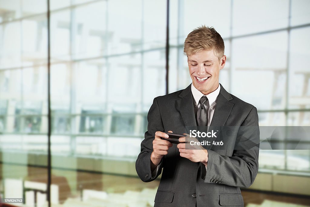 Uśmiechająca się Biznesmen przy użyciu telefonu komórkowego - Zbiór zdjęć royalty-free (20-29 lat)