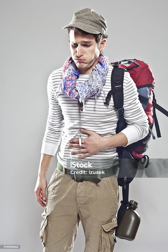 Nausea Young backpacker suffering from stomach ache. Studio shot, grey backgroound. Hangover Stock Photo